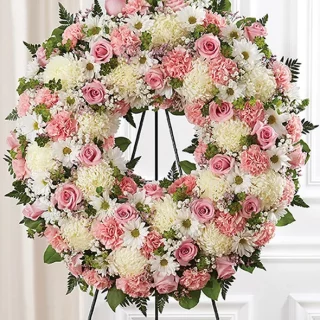 round funeral wreath of white pink and greenerys