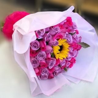 Express your love with our 'One in Million' bouquet featuring a stunning blend of purple and pink roses, accompanied by the radiant beauty of a sunflower.