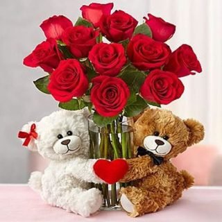 Order a prestigious Love Bouquet of two co-joined teddy bears, two dozen roses, and a clear vase. Share a moment of friendship, love, happiness, and joy