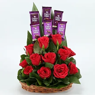 Order a summer holiday flower basket arrangement of red roses, greenery, and six dairy milk chocolates. express your feelings with chocolate and flowers today