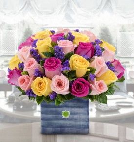 Friendship Bouquet of purple statice, blush pink roses, hot-pink and yellow roses, greenery's and a vase.