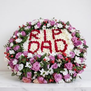 Last Respect Round Wreath with white chrysanthemums, purple roses, red hypericum and RIP DAD at the centre