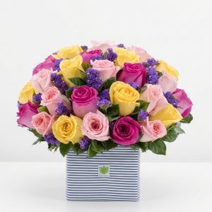 Friendship Bouquet with light pink, hot pink, and yellow roses, purple fillers, and greenery in a blue box