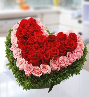 Winter Grace arrangement with red and pink roses, greenery's in a heart shaped flower box
