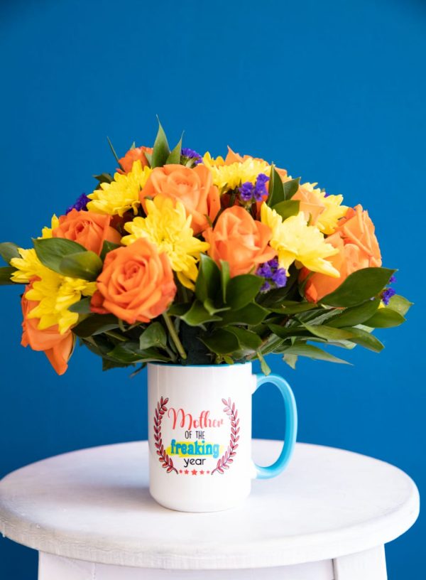 Celebrate the amazing moms in your life with this cheerful Mother of the Year mug arrangement. This unique gift is perfect for Mother's Day or any special occasion, featuring a message on the mug, fresh orange roses, yellow chrysanthemums, and purple accents. Enjoy Same-day flower delivery in Nairobi.