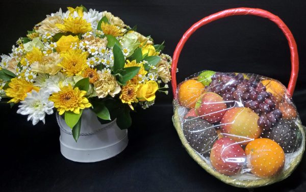 A festive gift set featuring a flower box with yellow and white blooms and a fresh fruit basket filled with an assortment of seasonal fruits.